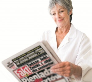 Woman in bedroom with newspaper smiling